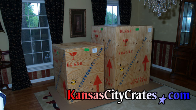2 Large chandelier wood crates are sitting on cardboard in home waiting for shipping.
