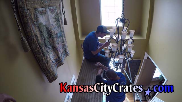 Crate builder sits 14' feet high on scaffolding to remove chandelier in foyer of Overland Park KS home