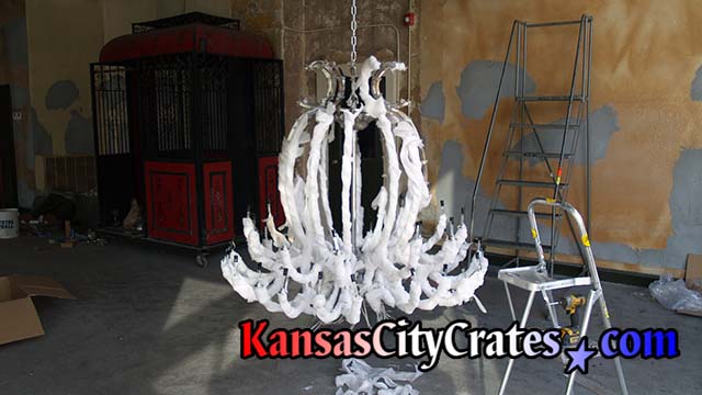 Protecting crystal chandelier with tissue paper before packing into crate