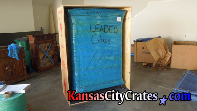 Bubble and stretch wrapped leaded glass cabinet loaded into crate
