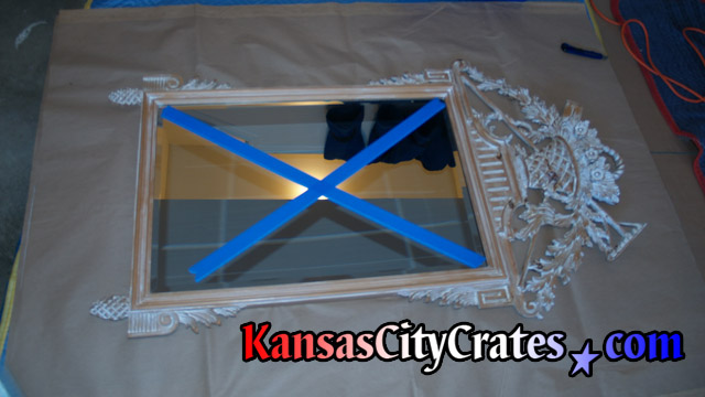 Blue painters tape on antique mirror with delicate crown.