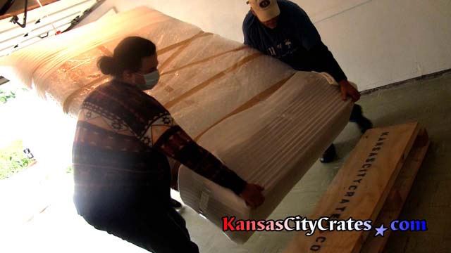 Crate personnel place wrapped core shell structured resin sculpture on base before packing into solid wall crate
