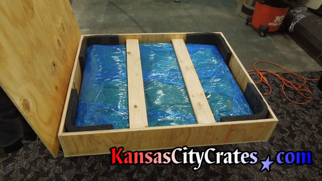 View of wood crate with lid removed showing  oil painting fully packaged and foam lining on shipping edges at Federal Government Office in Kansas City MO 64198